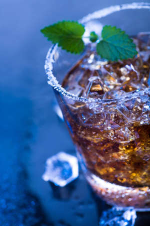 a glas with a rum, ice and lime cocktail