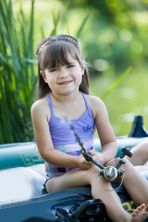 little girl fishing on lake at summerの写真素材
