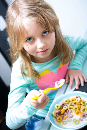 young girl eating cornflakes from the bowl
