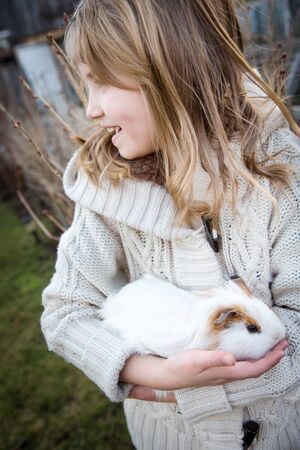 young girl playing with a cavy in the gardenの写真素材