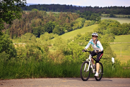A cycling woman in front of rural landscapeの写真素材