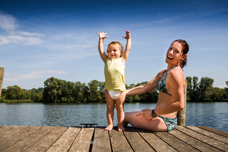 portrait of a young woman with daughter at lakesideの写真素材