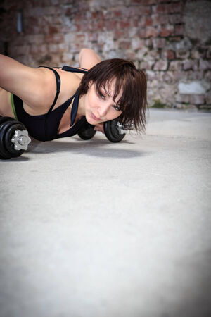 young woman with barbells at fitness exercise in a gymの写真素材