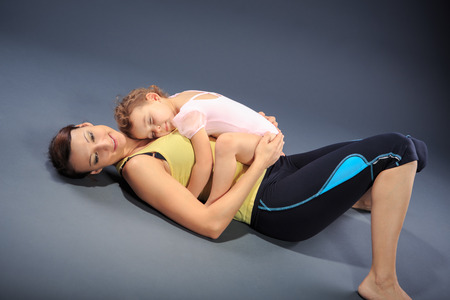 Studio shot of a little girl with mother at fitness exerciseの写真素材