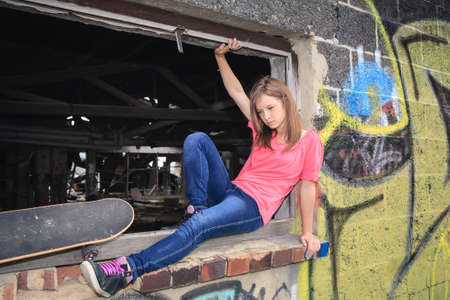 portrait of a young teenage girl with skateboard in front of urban background