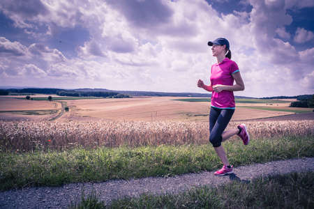 a woman running through the rural landscapeの写真素材