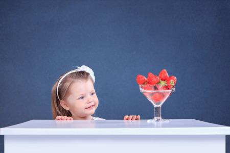 studio portrait of a little girl with strawberriesの写真素材