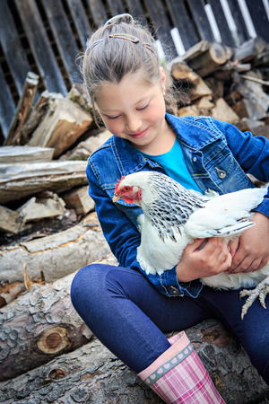 little girl with a hen in front of the farmの写真素材