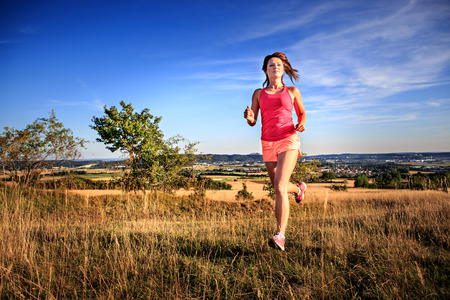 young woman jogging in front of rural landscapeの写真素材