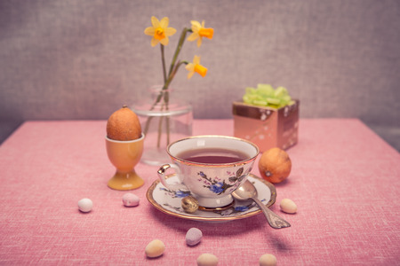 The easter installation with a cup, narcissi and sweetsの写真素材