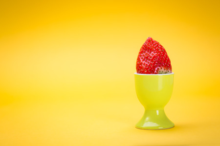 the easter installation with eggcup and strawberryの写真素材