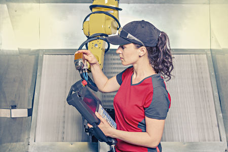 A young female technician while machine constructing in a manufacturing plantの写真素材