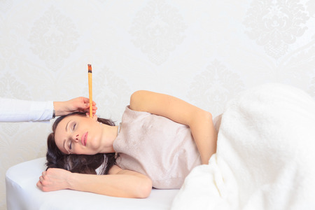 a young woman by ear candles treatment at the beauty salon