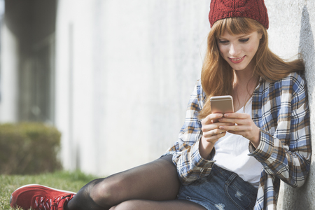 a casual young woman using an application to send a text message in her smart phone deviceの写真素材