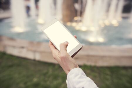 female hand holding a smart phone with a blank white screen mockupの写真素材