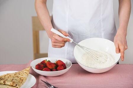 close up on female hands whisking flour while preparing crepesの写真素材