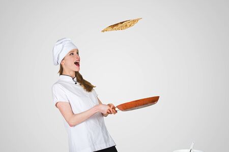 female chef is flipping a crepe in the air using a frying panの写真素材