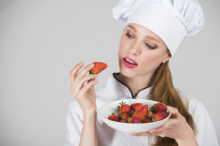 female chef is holding a plate of strawberries, examining oneの写真素材