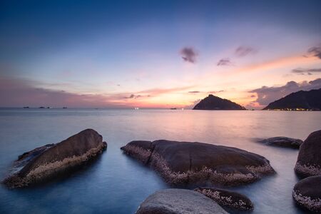 Longh exposure sunset by the sea with islands rocks and cloudsの写真素材
