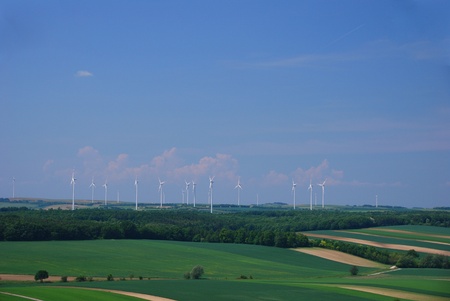 many wind turbines are in an area with fieldsの写真素材