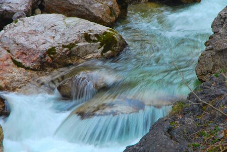 cold blue water flowing waterfall in the mountains in summerの写真素材
