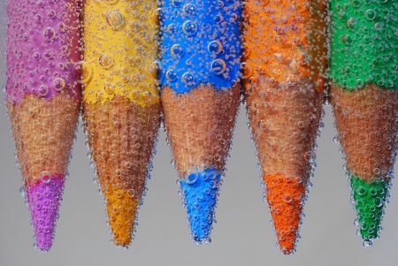 five colored pencil with many peaks in the water and bubblesの写真素材
