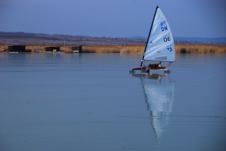 individual ice boaters on glassy frozen lake in winter with reflectionのeditorial素材