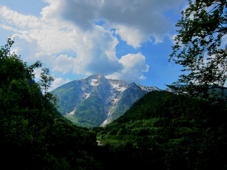 beautiful mountain with snow between green mountains in the summerの写真素材