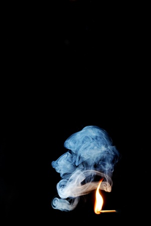 swirling blue gray smoke from match with bright flameの写真素材