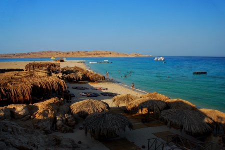 Beautiful beach on blue sea with sun shield of reeds on vacationの写真素材