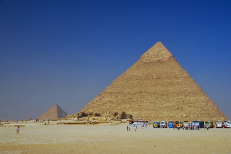 high pyramids in egypt with blue sky and lots of buses with tourists