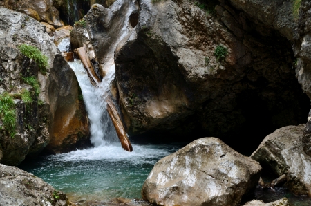 waterfall with rocks and wood trunk the mountainsの写真素材