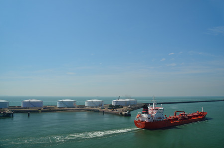 big red cargo ship in a harbor near the sea