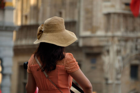 young woman stands in the city wearing a hat when sightseeingの写真素材