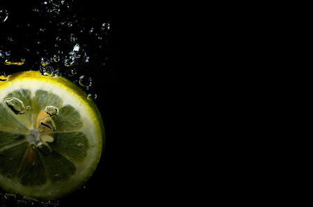fresh juicy lemon falls into water with bubblesの写真素材