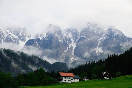 high Dachstein with fog and houses in the mountainsの写真素材