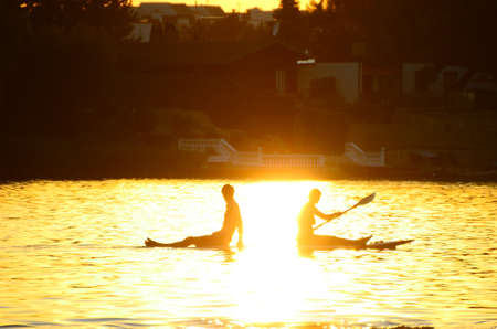 Young couple sitting on surfboard and paddling in the sundownの写真素材