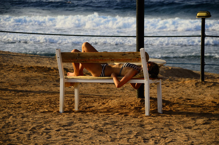 young woman in bikini sleeping on the sandy beach near the seaの写真素材