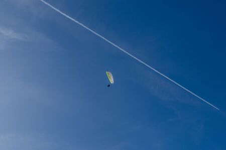 paragliders with airplane at blue sky