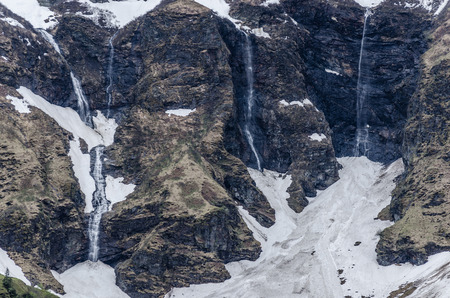 small waterfalls with snow in the mountains