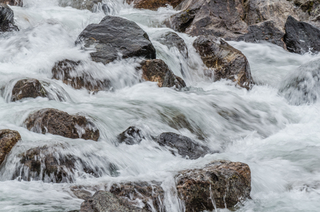 foaming water over rocks in streamの写真素材