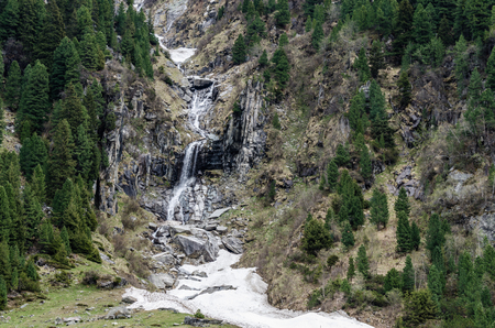 waterfall with snow on mountain in springの写真素材
