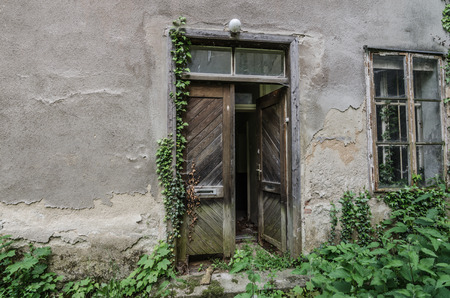 door of wood and old overgrown houseの写真素材