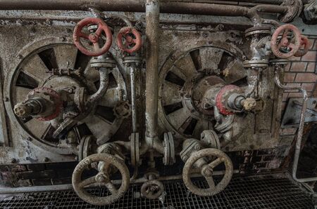 many rusty pipes and valve wheels