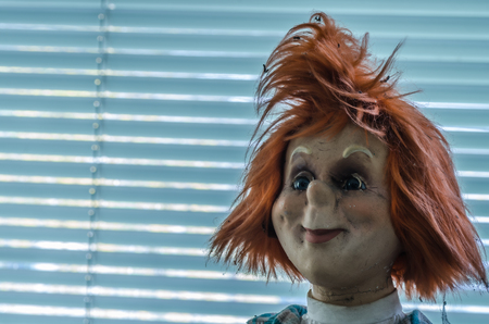 head of a doll with red hair in an old houseの写真素材