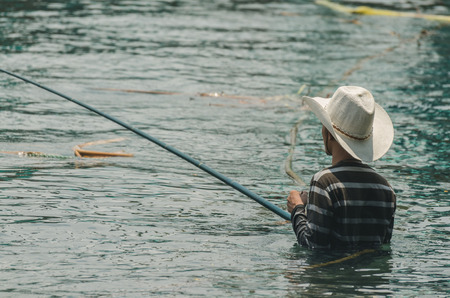 man with cowboy hat while fishing in the seaの写真素材