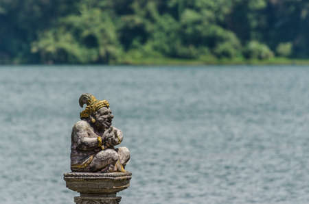 sitting statue in temple at lake in baliの写真素材