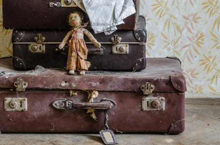 old doll with suitcase in an abandoned houseの写真素材