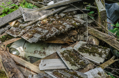 Old car under roof tile of a houseの写真素材
