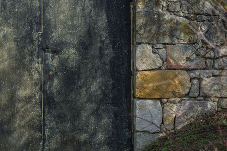 Iron door with a stone wall of a houseの写真素材